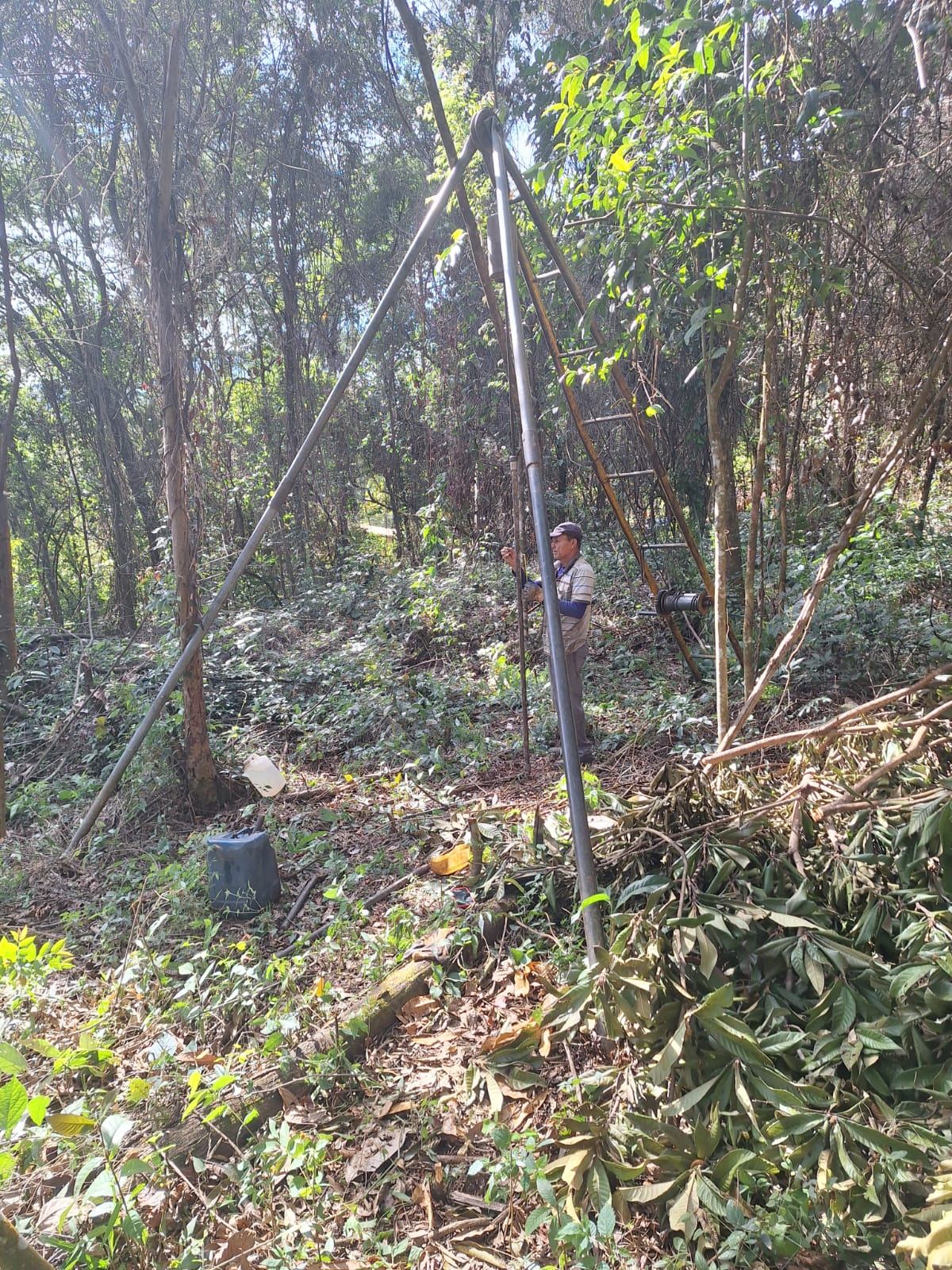 Equipe montando tripé de sondagem SPT em área de mata